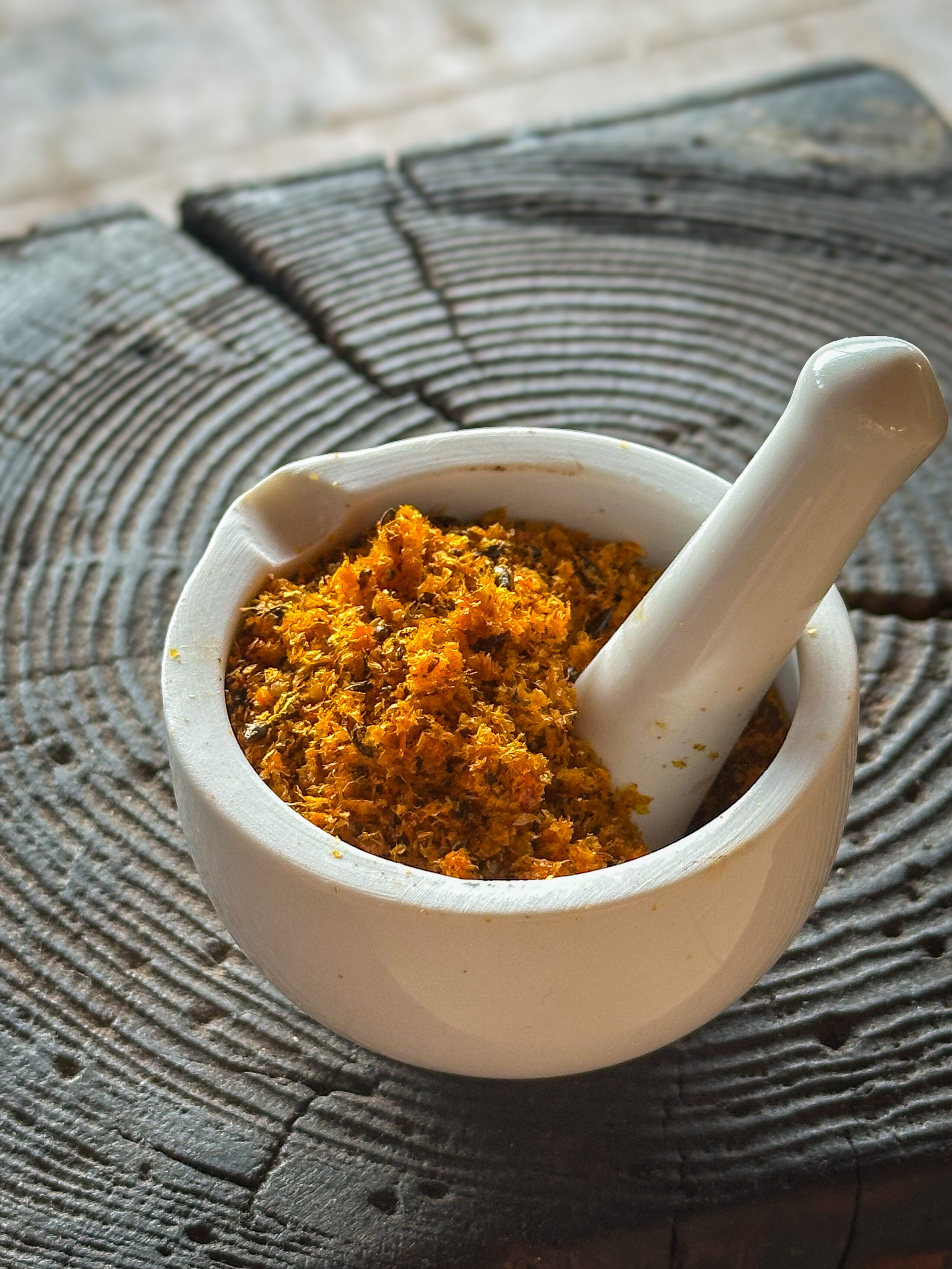 Kuivatatud ja jämedalt jahvatatud astelpaju pressijääk uhmris puidust pinnal