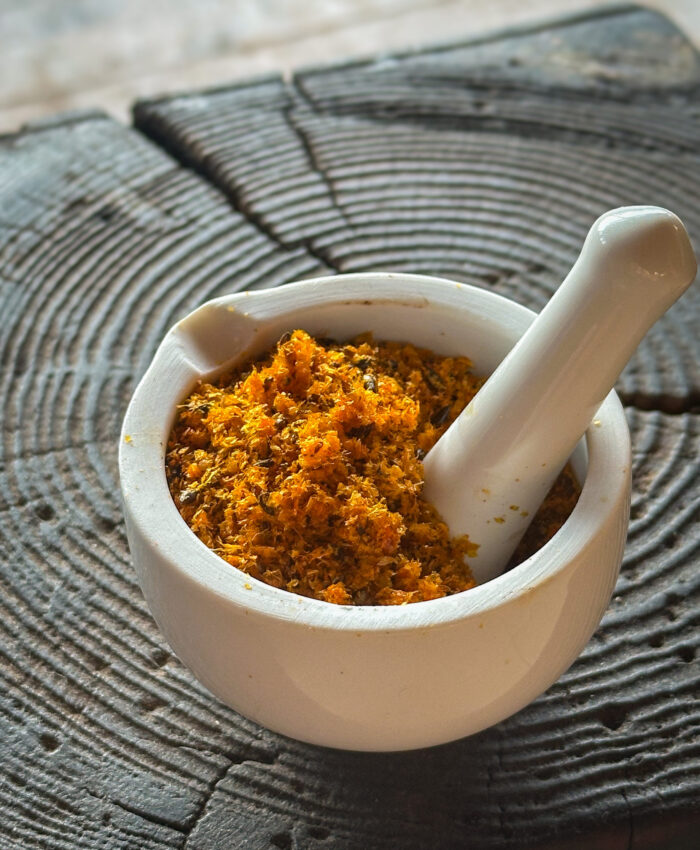 Kuivatatud ja jämedalt jahvatatud astelpaju pressijääk uhmris puidust pinnal